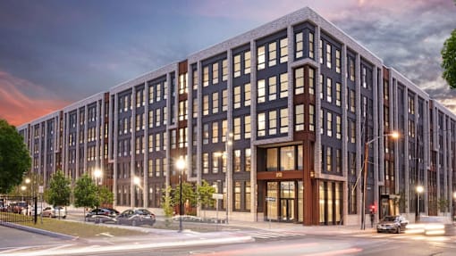 A modern multi-story building with a parking lot in front.
