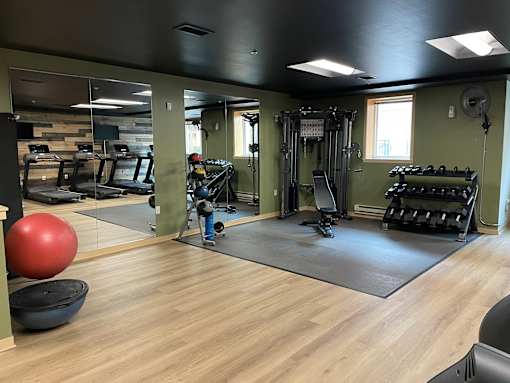 A gym with a variety of equipment including weights and a squat rack.