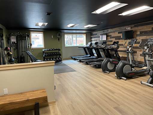 A gym with treadmills, elliptical machines, and dumbbells.