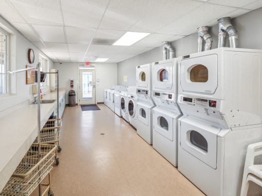 a laundromat with a row of washes and dryers in a room