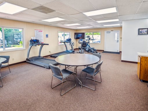a gym with a table and chairs and a treadmill