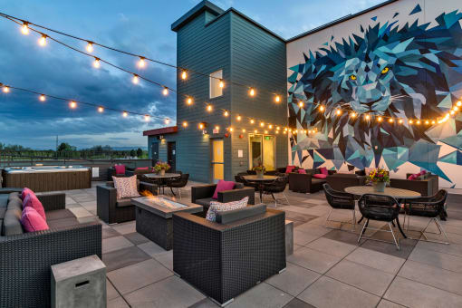 a patio with tables and chairs and a mural on the side of a building  at West Line Flats, Lakewood, CO, 80214