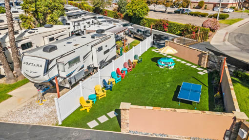 an aerial view of an rv park with a tennis court and lounge chairs