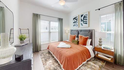 A bedroom with a bed in the center and a white vase on a dresser.