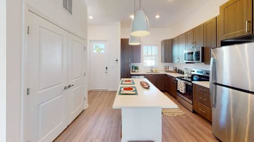 A kitchen with a white island in the middle and a refrigerator on the right.