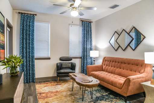 A living room with a brown couch, a chair, a table, and a potted plant. at Centre Pointe Apartments, Melbourne, 32940