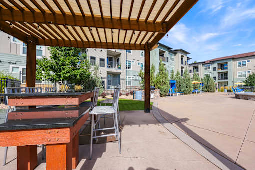 Table and Chair Set Under a Wooden Roof at WestLink at Oak Station Apartments, Lakewood, CO, 80215