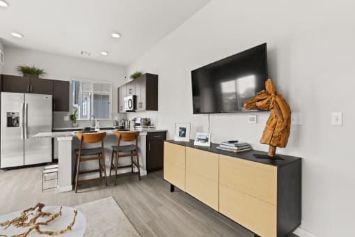 a kitchen and living room with a large tv on the wall and a wooden horse statue on at The Villas at Prairie Center, Brighton, CO