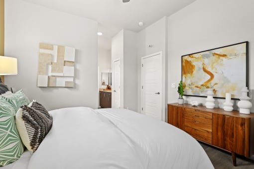 a bedroom with a large white bed and a wooden dresser at The Villas at Prairie Center, Colorado