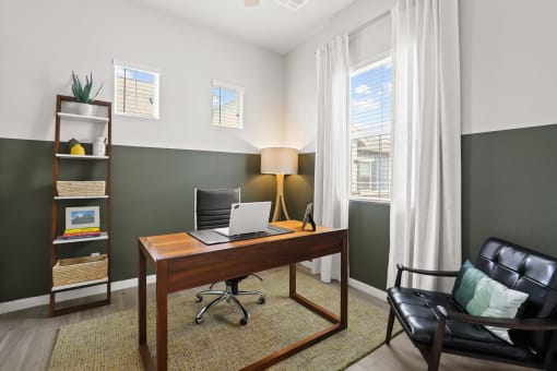 a desk with a laptop and a chair in a room with two windows at The Villas at Prairie Center, Colorado
