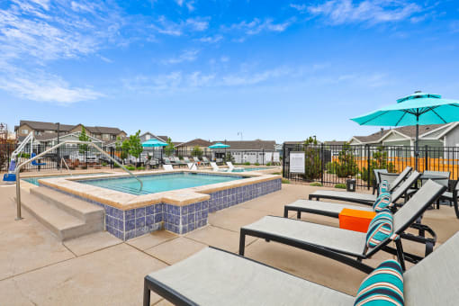 the reserve at bucklin hill pool and hot tub with lounge chairs and umbrellas at The Villas at Prairie Center, Colorado, 80601