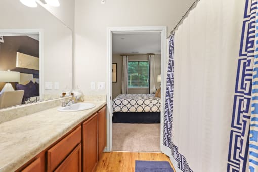 a bathroom with a shower and a bed in the background