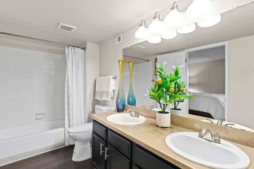 a bathroom with two sinks and a mirror and a toilet at Silver Reef Apartments, Lakewood, CO, 80228