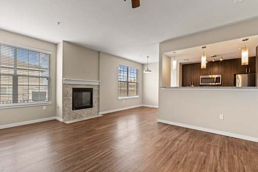 a living room with a fireplace and a kitchen in the background