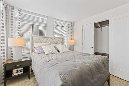 a bedroom with a bed and two windows at 8000 Uptown Apartments, Colorado 80021