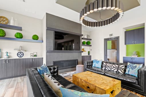 a living room with black leather couches and a wooden coffee table