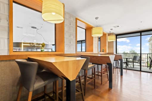 a dining area with wooden tables and chairs and a large window with a view of the outdoors