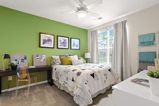 a bedroom with green walls and a white desk with a computer
