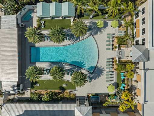 A swimming pool surrounded by palm trees and lounge chairs. at Centre Pointe Apartments, Melbourne, FL