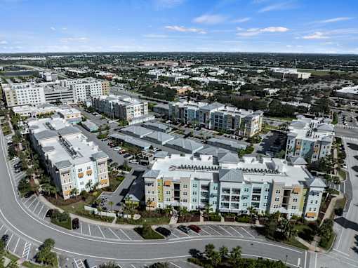 A large, modern complex of buildings with a parking lot in front. at Centre Pointe Apartments, Melbourne, FL