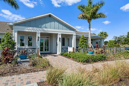 a house with a porch and a palm tree in front of it at Artesia at Lakewood Ranch Apartments, Bradenton, Florida