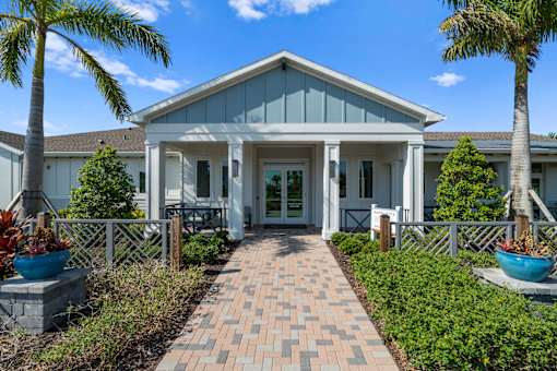 the front of a house with a walkway and palm trees at Artesia at Lakewood Ranch Apartments, Bradenton, FL