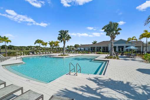 a swimming pool with palm trees and a building in the background at Artesia at Lakewood Ranch Apartments, Florida 34211