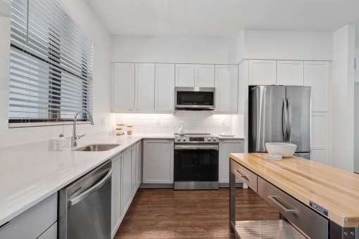 a kitchen with white cabinets and stainless steel appliances and a wooden counter top at Odyssey, Fort Myers, FL, 33905