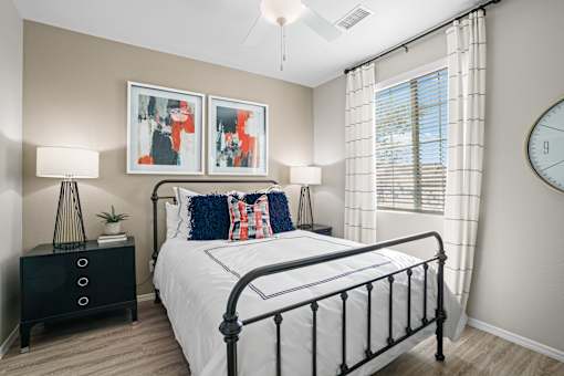 an empty bedroom with a bed and a clock on the wall at Soleil at Canyon Trails Apartments, Goodyear, AZ, 85338