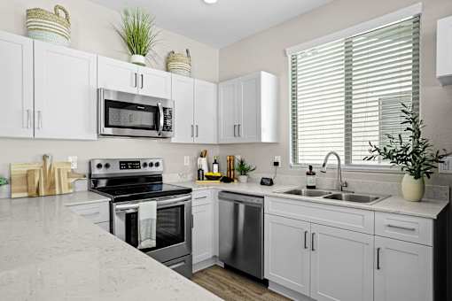a modern kitchen with white cabinets and stainless steel appliances at Soleil at Canyon Trails Apartments, Goodyear, 85338