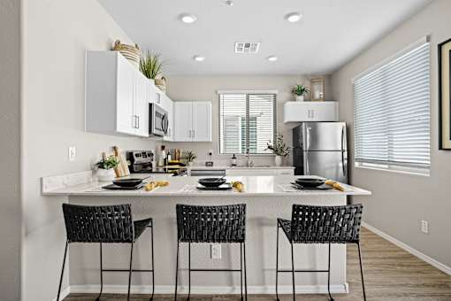 an open kitchen with a large island with three black stools at Soleil at Canyon Trails Apartments, Goodyear, AZ, 85338