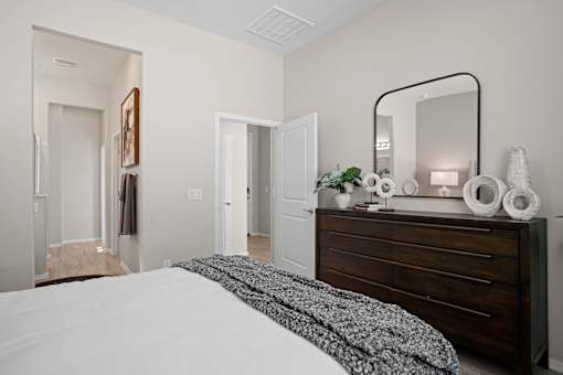 a bedroom with a large bed and a dresser with a mirror at Soleil at Canyon Trails Apartments, Goodyear, Arizona