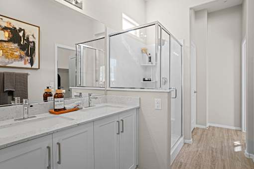 a bathroom with two sinks and a mirror and a shower at Soleil at Canyon Trails Apartments, Goodyear, 85338
