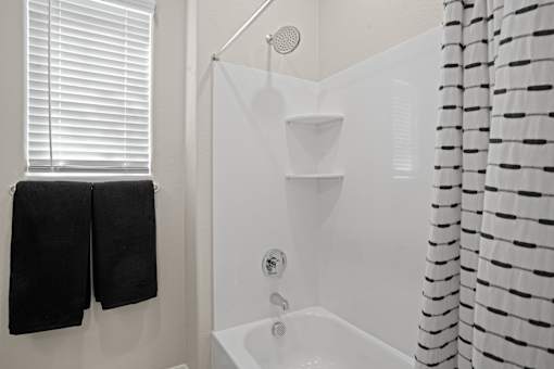 a white bathroom with a shower and black towels at Soleil at Canyon Trails Apartments, Arizona