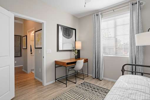 a bedroom with a desk and a mirror and a window at Soleil at Canyon Trails Apartments, Arizona, 85338