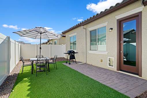a backyard patio with a table and chairs and an umbrella at Soleil at Canyon Trails Apartments, Goodyear, AZ, 85338