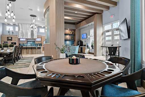 A poker table is surrounded by chairs in a room with a bar area in the background. at Centre Pointe Apartments, Florida, 32940