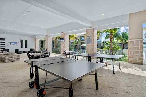 A ping pong table is in the middle of a room with a white ceiling and a glass wall outside. at Centre Pointe Apartments, Melbourne