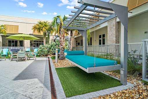 A patio with a swing bed and a table with chairs. at Centre Pointe Apartments, Melbourne