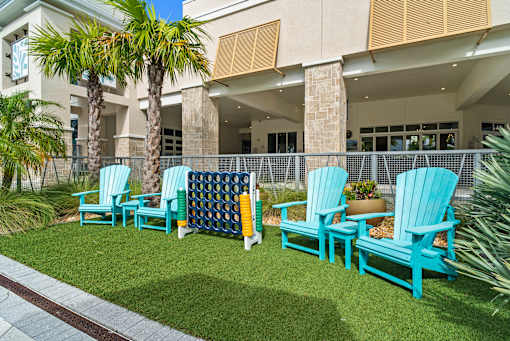 A row of blue chairs are arranged on a lawn. at Centre Pointe Apartments, Melbourne, FL, 32940