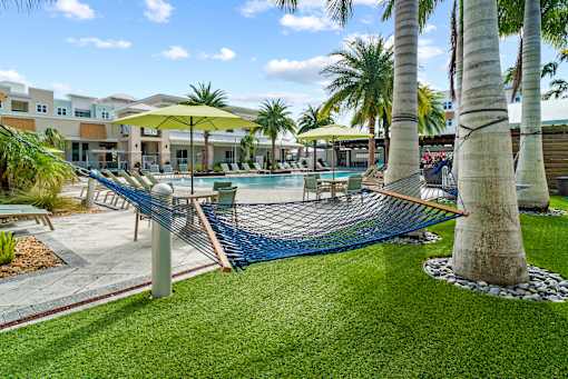 A pool area with a hammock and palm trees. at Centre Pointe Apartments, Florida