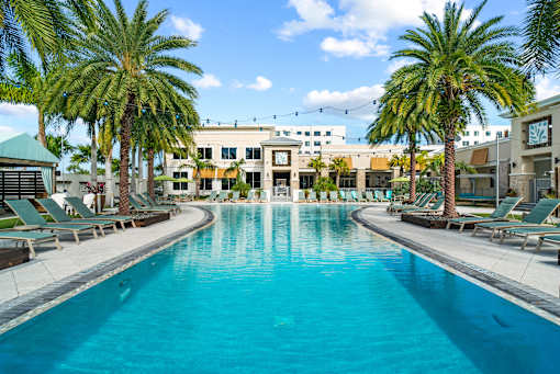 A large swimming pool surrounded by palm trees and lounge chairs. at Centre Pointe Apartments, Melbourne
