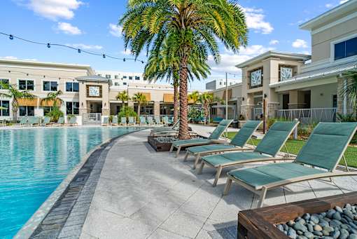 A pool area with lounge chairs and a palm tree. at Centre Pointe Apartments, Melbourne, FL, 32940