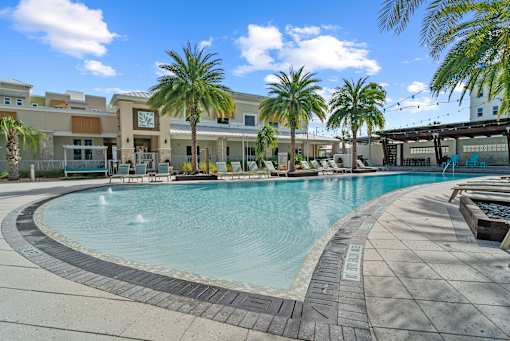 A large outdoor swimming pool surrounded by palm trees and lounge chairs. at Centre Pointe Apartments, Florida