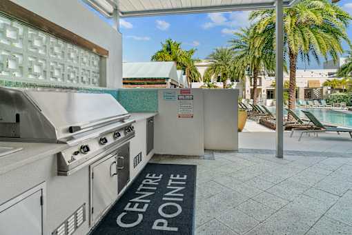A kitchen area with a grill and a pool in the background. at Centre Pointe Apartments, Melbourne, FL, 32940