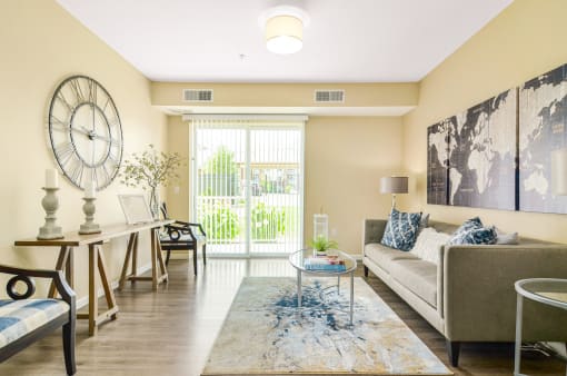 a living room with beige walls and a large clock on the wall at Skye at Arbor Lakes, Maple Grove, 55369