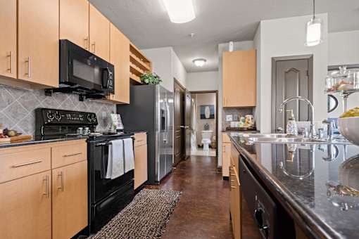 a kitchen with stainless steel appliances and wooden cabinets at The Millennium Towne Center Apartments, Baton Rouge
