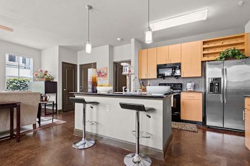 a kitchen with stainless steel appliances and an island with bar stools at The Millennium Towne Center Apartments, Baton Rouge, LA