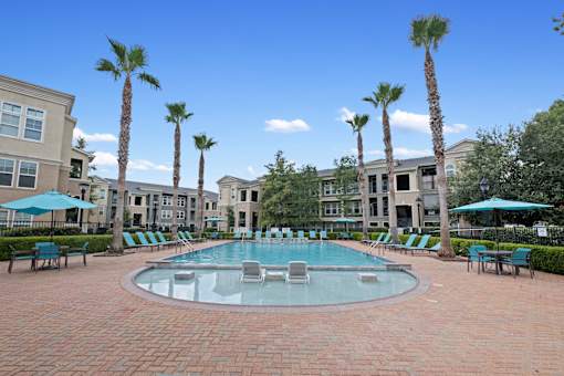 a large pool with chairs and umbrellas in front of apartment buildings at The Millennium Towne Center Apartments, Baton Rouge, LA, 70806