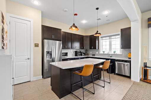 a kitchen with a large island with three chairs and a stainless steel refrigerator at The Landing Apartment , Hazlet, 07730